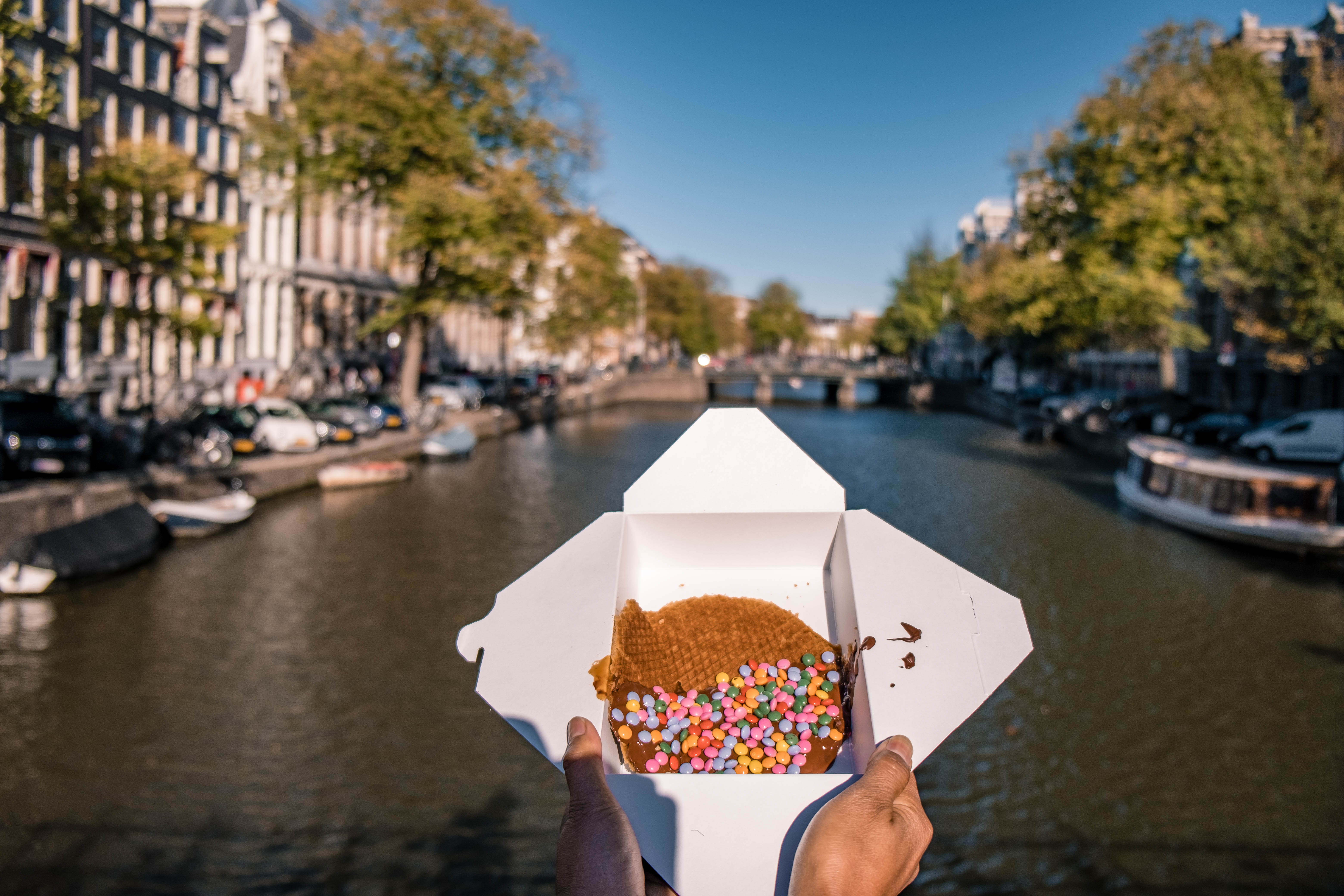 woman hand with Stroopwafel in Amsterdam - typical Dutch food - two circular pieces of waffle filled with caramel-like syrup.